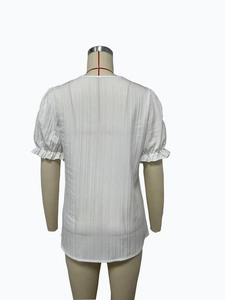 Detail of white short sleeve blouse featuring textured vertical stripes and ruffled cuffs