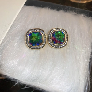 Détail de boucles d'oreilles carrées vintage avec pierres colorées et halo sur fourrure