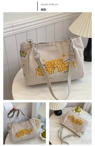Close-up of off-white canvas tote bag with yellow embroidery and chain shoulder strap