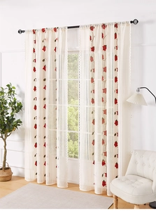 Close-up of white lace curtain with festive red poinsettia embroidery in a cozy home setting