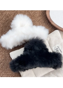 Detail of plush faux rabbit fur claw clips in black and white on a cozy knit fabric background