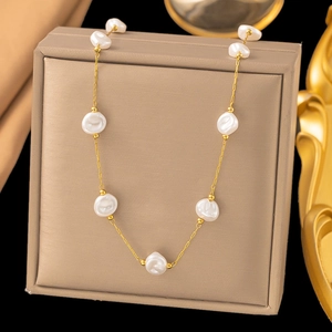 Minimalist gold necklace with natural baroque pearls over luxury jewelry box display