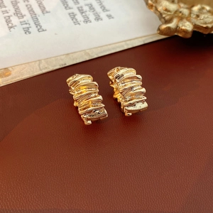 Macro shot of gold-plated hoop earrings with irregular wrinkled metallic texture