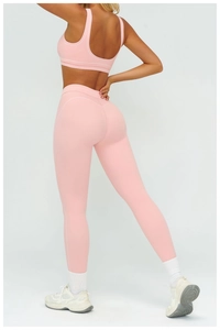 Detailed view of high-waist pink yoga leggings and matching sports bra set on a model