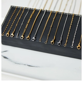 Detail view of various gold and silver titanium steel necklaces with lobster clasps
