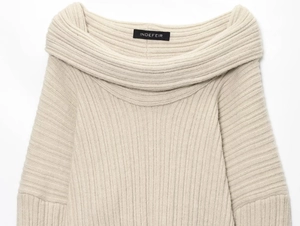 Close-up of beige ribbed knit sweater collar with black branded neck label detail
