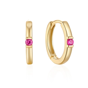 Detail view of gold huggie hoop earrings featuring a single round pink gemstone inlay