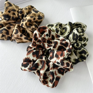Three leopard print satin scrunchies in brown and green tones on white background