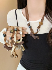 Detail of dachshund pendant necklace with silk cord and decorative bone beads