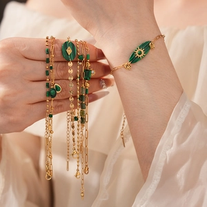 Gros plan de bracelets vintage dorés avec pendentifs en malachite verte au poignet