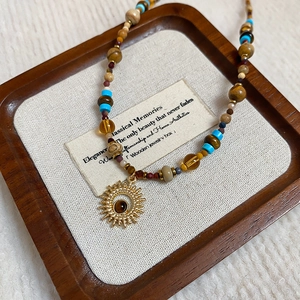 Detail of beaded necklace with sun pendant on a vintage wooden display tray