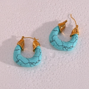 Macro detail of turquoise texture earrings with gold accents on a water droplet surface