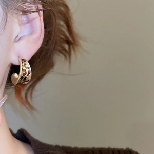 Vue détaillée de boucles d'oreilles créoles avec motif léopard doré et marron