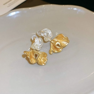 Macro shot of gold floral earrings with delicate ruffled petals and white pearl centers