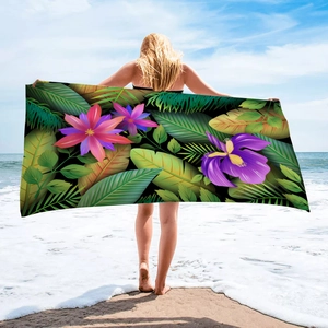 Detail of microfiber beach towel featuring vibrant tropical floral and palm leaf prints