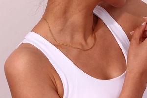 Close-up of minimalist gold plated stainless steel S-chain necklace worn by a model