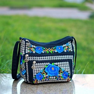 Detail of multi-layer zipper compartments on black canvas bag with ethnic embroidery