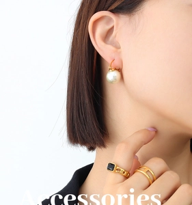 Gros plan de boucles d'oreilles perles dorées 18K et bague pierre noire