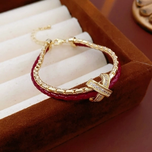 Detail of red braided leather gold bracelet with a zircon-encrusted X-cross element