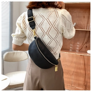 Detail of black pebbled leather belt bag with gold zippers and wide shoulder strap