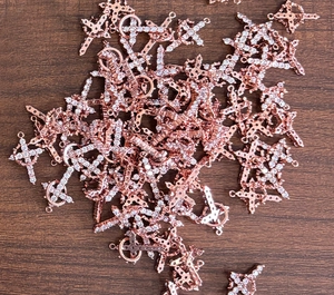 Macro view of rose gold cross pendants with pavé set cubic zirconia on wood surface