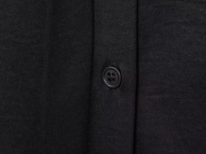 Close-up of black fabric texture with matching four-hole button on the placket