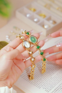 Detail view of gold women's bracelet watches with pearl and green jade stone inlay