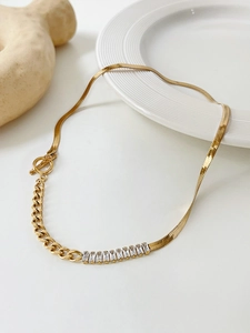 Detail of gold OT clasp necklace featuring zircon inlay and snake chain stitching