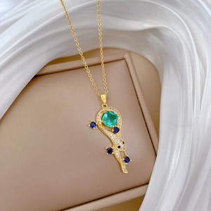 Detailed macro view of a gold snake pendant with green gem on white silk