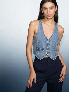 Detail of light blue denim vest with V-neckline and metal buttons in a slim fit style