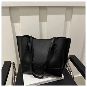Borsa tote minimalista in pelle nera su sedia moderna con luce naturale e soffusa