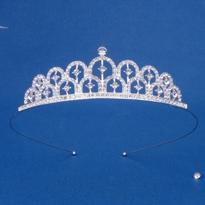 Dettaglio ravvicinato di una tiara argentata con strass e archi su uno sfondo blu