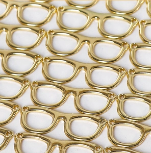 Macro array of golden glasses-shaped alloy pendants for DIY handmade jewelry crafting
