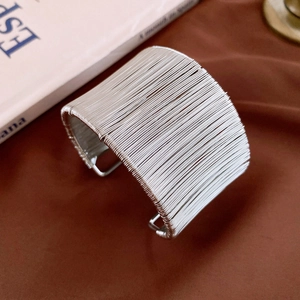 Détail d'un large bracelet manchette en fils d'argent multicouches au design industriel épuré