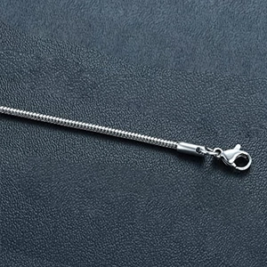 Macro shot of silver snake chain necklace featuring a secure lobster clasp closure