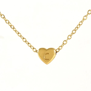 Detail shot of a gold heart pendant with letter C engraving on a fine O-link chain
