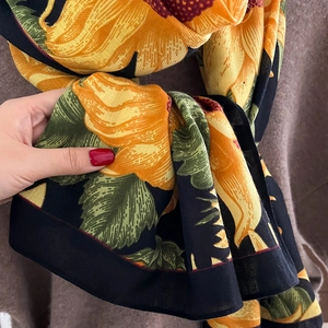 Detail shot of lightweight sunflower print scarf with vibrant yellow and green floral patterns