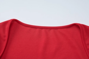 Détail de la texture du tissu rouge et coutures précises sur le décolleté de la robe