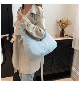 Detail of light blue quilted crescent bag showing the soft padded nylon texture and strap