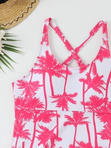 Flat lay of tankini top with pink palm tree print, straw hat and summer leaves detail