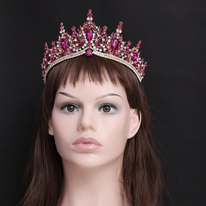 Detail of bridal gold crown with burgundy crystals and rhinestones on black background