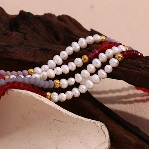 Detailed close-up of handmade necklace with white pearls and red faceted crystal beads