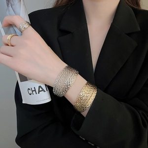 Detail of layered gold and silver textured metal bracelets and rings for women