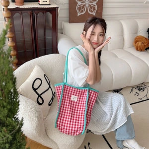 Red and white checkered tote bag with light blue straps shown in a cozy home setting