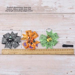 Close-up of Halloween bow hair clips set with pumpkin and spider resin details