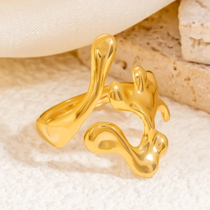 Macro shot of gold fluid irregular ring on textured stone and white fabric background