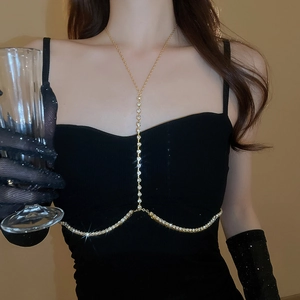 Dettaglio della catena per il corpo dorata con strass lucidi su un abito nero