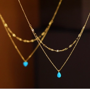 Close-up of double layer gold necklace with blue teardrop opal pendant and fine chain