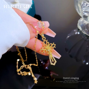 Close-up of elegant gold titanium steel cross necklace held by a manicured hand