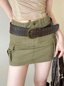 Detail of vintage brown studded belt with metal buckle on army green cargo mini skirt